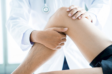 Close-up of male physiotherapist massaging the leg of patient in a physio room.